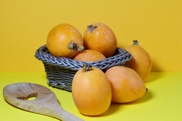 Close up, group of medlars on a light background and a wicker basket.