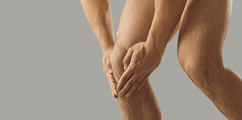 Crop close up of naked man hold knee suffer from acute spasm. Pain in kneecap. Male struggle with ache, have muscular strain or nerves inflammation. Trauma or injury concept. Healthcare.