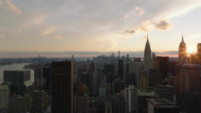 Aerial descending footage of large city at dusk. Various tall buildings against sunset sky. Iconic Chrysler and Empire State buildings. Manhattan, New York City, USA