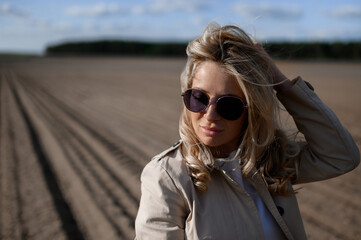 Beautiful blonde caucasian girl in sunglasses in the field on a sunny day