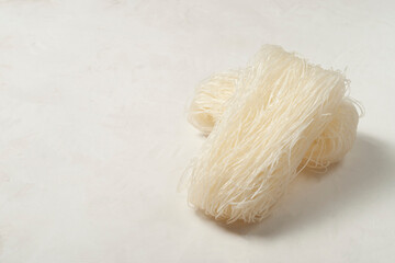 skeins of raw Korean starch noodles tanmen lie on top of each other on a gray background, side view, copy space.