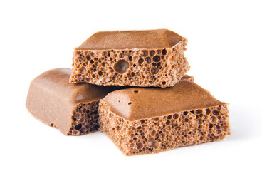 Pieces of porous milk chocolate lying in a pile on a white isolated background.