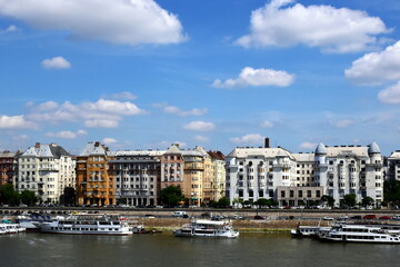 Fototapeta premium Budapest skyline with residential buildings along the Danube river. white boats moored along the shore line. bright light residential apartment buildings day traffic. travel and tourism concept