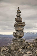 Exceptionally tall cairn made of twelve stones on the rim of a crater in a desolate mountain landscape near lake Myvatn in Iceland