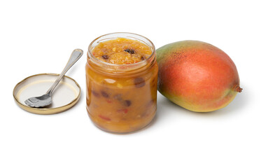 Glass jar with homemade mango chutney and a fresh mango isolated on white background