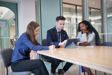 Obraz premium Image of young businessmen and colleague discussing document in laptop and touchpad at meeting