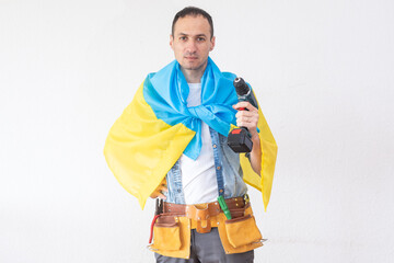 repairman standing with a drill in a hand and with the flag of Ukraine
