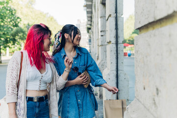 Two young Asian girls shopping in a clothing store window.