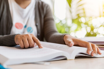 Close up hands college student pointing and reading textbook for preparing exam.