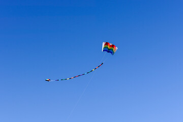 Multicolored rainbow kite flying in blue sky
