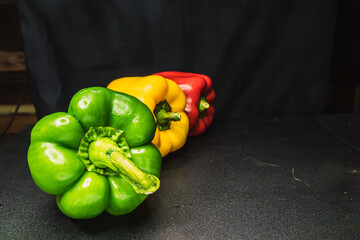 Orange yellow red bell peppers green peppers  on dark background 