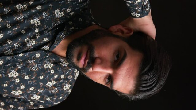 hair commercial concept. vertical studio shot of a handsome cuban bearded black-haired man in his 30s looking at camera and touching his hair in a seductive manner. High quality 4k footage