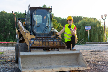 Cheerful female excavator operator on construction site.