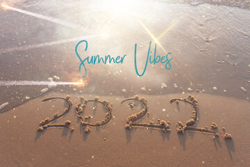 The word summer 2022 written in sea sand. Warm sunset time, vacation and enjoyment