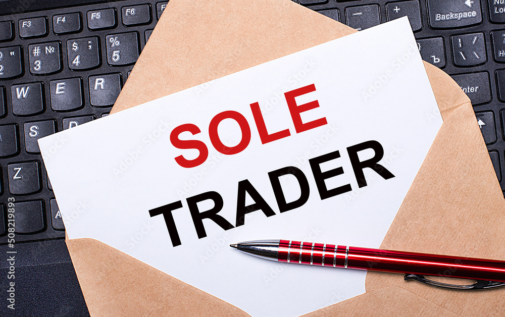 Aufkleber white card with the text sole trader in a craft envelope on a work desk with a modern laptop keyboar