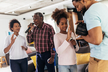 Family singing karaoke with microphones at home