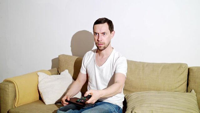 Young man switch at living room. Home vacation sofa portrait. Watch tv video. Alone in interior. Happy emotion. Smiling male person. Lifestyle action. House light background