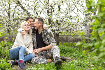 Happy soldier with family in park.