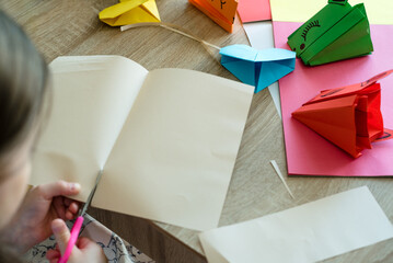 Children's hands make origami from colored paper. Origami hearts and dragons. Origami lesson.