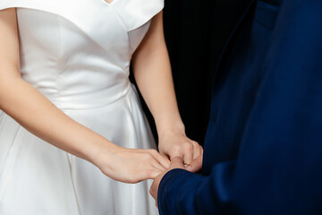 the groom in a blue suit holds the hands of his bride