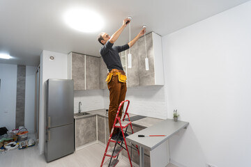 Concept update of the ceiling lamp in the room. A happy Man on a stepladder points to the ceiling.