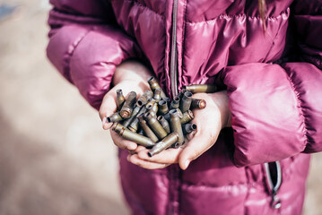 War in Ukraine in the city of Mariupol. bullet casings in the hands of a child. Russian military aggression