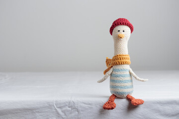 Cute handmade crochet knitted amigurumi toy goose, sailor in red hat and yellow scarf, sits on the...