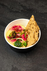 Hummus. A dish of crushed chickpeas for delivery, or online store. Isolated on a dark background. Healthy food delivery concept.