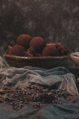 Craft chocolate truffles on plate with cocoa powder and anise, cinnamon, cardamom.