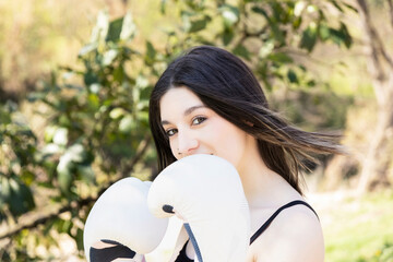 young female boxer with white gloves in a park