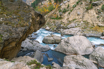 A huge gray boulder lies in a mountain river. A mountain river with clear and transparent water....