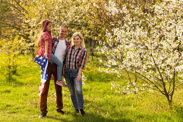 Obraz premium portrait of beautiful modern american family with USA flag outdoors.