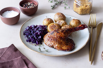 Baked duck leg with potatoes and red cabbage.