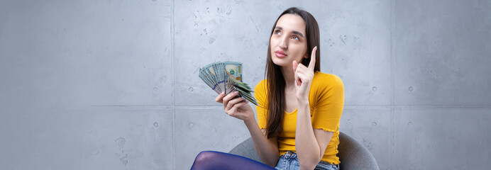 Photo of a wealthy woman in simple clothes holding a fan of dollar money isolated against a...
