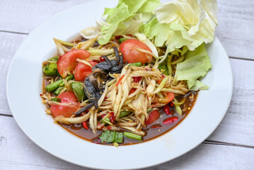 Thai food papaya salad with cabbage yard long bean on white plate , papaya salad with crab and fermented fish