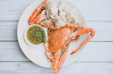 seafood plate fresh crab cooking on white plate background , blue swimming crab meat claw served on a food table - cooking steamed crab with seafood sauce top view © Bigc Studio