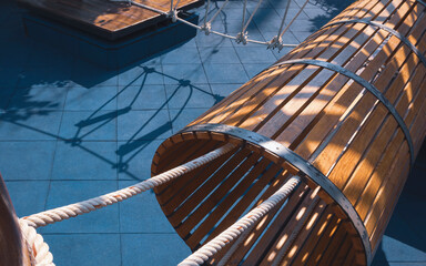 Sunlight and shadow on surface of vintage wooden tunnel and rope bridge on blue rubber tile floor in playground area at public park