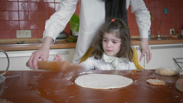 Muslim family spend time in the kitchen. Mom let her tearful daughter roll out the dough