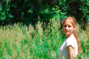 Girl on a summer day among tall grass