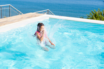 Closeup portrait of cute little arabic girl swimming in the pool, happy child having fun in water, beach resort, summer vacation and holidays concept