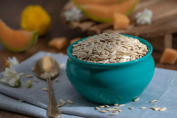 Edible dried raw organic seeds of musk melon or cantaloupe or tati or honeydew on a wooden surface.