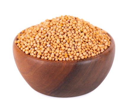 Mustard seeds in wooden bowl, isolated on white background. Pile of dry mustard grains.