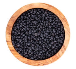Black lentils in olive bowl, isolated on white background. Dry beluga lentil grains pile. Top view.
