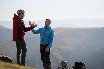 Paragliders high fiving after walking up hill to paragliding starting point, on a sunny morning in...