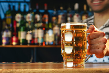 Barman serves glass of cold beer at bar counter in pub