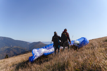 Rear view of paraglider is preparing for the flight on mountain. Extreme sports activity.