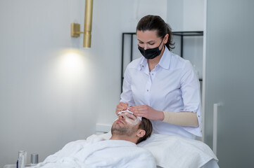 Cosmetologist removing the facial mask from the clients face