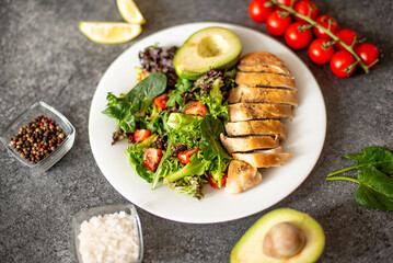 Grilled chicken meat and fresh vegetable salad of tomato, avocado, lettuce and spinach. Healthy and detox food concept. Ketogenic diet.