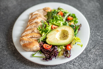Grilled chicken meat and fresh vegetable salad of tomato, avocado, lettuce and spinach. Healthy and detox food concept. Ketogenic diet.