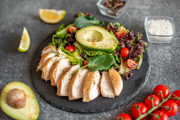 Grilled chicken meat and fresh vegetable salad of tomato, avocado, lettuce and spinach. Healthy and detox food concept. Ketogenic diet.